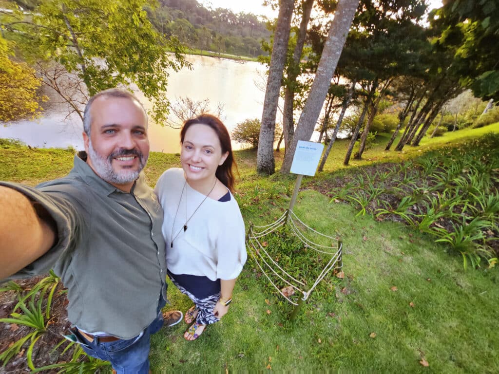 Selfie de Leonardo Merçon e sua esposa ao lado da colmeia protegida de jataí-da-terra na Reserva Águia Branca, destacando a estrutura de conservação aprimorada.